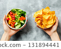 Unhealthy vs healthy food. vegetable salad and potato in different hands on green background . Choice between fast foods and vegetables, fruit. 131894441