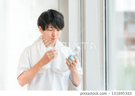 A young Asian man taking care of his bad breath by using mouthwash in the morning 131895383