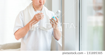 A young Asian man taking care of his bad breath by using mouthwash in the morning 131895385