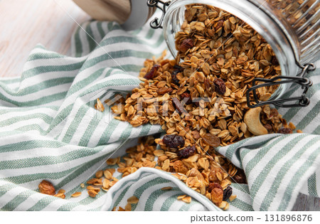 Granola pouring from jar on striped cloth Granola pouring from jar on striped cloth 131896876