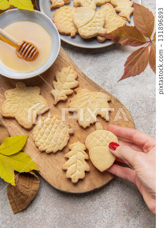 Hand holding fall themed shortbread cookies with honey Hand holding fall themed shortbread cookies with honey 131896893