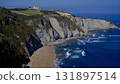 A breathtaking wide shot of the rugged coastline in Gijon, Asturias, Spain, featuring steep, layered cliffs covered with rich greenery 131897514