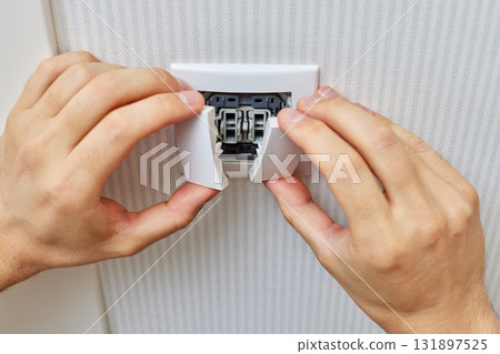 male hands of electrician installing white two-key electric light switch at home. Replacing. 131897525