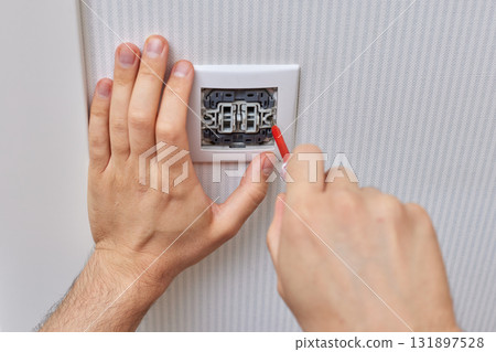 electrician installing electric light switch using screwdriver at home, close-up electrician installing electric light switch using screwdriver at home, close-up 131897528