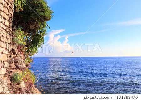 Picturesque view of sea, medieval wall and tourist on a parachute, Budva, Montenegro. Topic of summer vacation, leisure and adventure for tourist. A popular tourist pastime with a parasailing Picturesque view of sea, medieval wall and tourist on a parachute, Budva, Montenegro. Topic of summer vacation, leisure and adventure for tourist. A popular tourist pastime with a parasailing 131898470