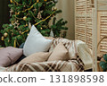 cozy indoors with Christmas tree, blankets, cushions, creating warm atmosphere for holiday. closeup. 131898598