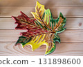 clay dish in shape maple leaf crafted in vibrant autumn colors on wooden table. closeup. 131898600