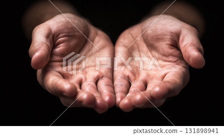 Open Hands: A person presents their open palms, offering a sense of vulnerability, generosity, or anticipation against a dark backdrop. 131898941