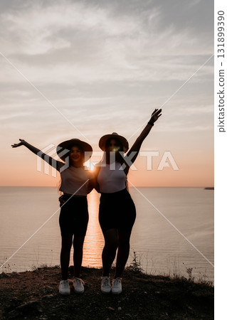 Silhouettes of Two Women Embracing Against Sunset Silhouettes of Two Women Embracing Against Sunset 131899390