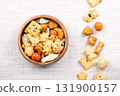 Japanese rice crackers, in wooden bowl, on linen. Assorted varieties of Arare crackers made from baked rice flour, brushed with soy sauce and vinegar for a smooth texture, some sprinkled with seaweed. 131900157
