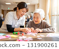 這是日託中心的場景，護理人員和老年婦女一邊微笑一邊享受手工藝的樂趣。 131900261