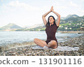 Woman meditating by the sea calmness harmony and connection with nature peaceful outdoor wellness scene 131901116