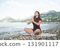Meditation and yoga on beach woman with sea view promoting health balance and mindfulness in nature 131901117