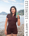 Young woman drinking water after intense workout on the beach outdoor fitness and healthy lifestyle scene 131901122