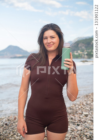 Young woman drinking water after intense workout on the beach outdoor fitness and healthy lifestyle scene Young woman drinking water after intense workout on the beach outdoor fitness and healthy lifestyle scene 131901122