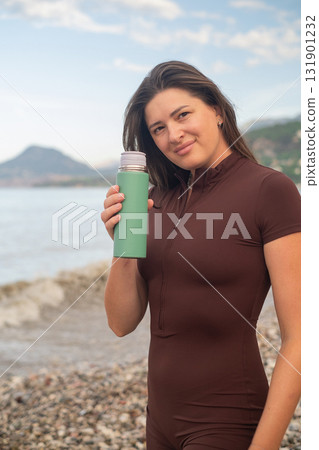 Woman enjoying peaceful seaside morning, refreshing body with water after sport activity. 131901232