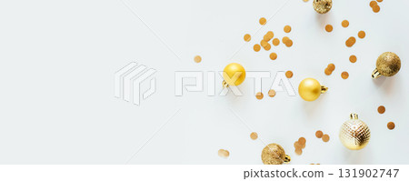 Golden Christmas balls and confetti on a white table Golden Christmas balls and confetti on a white table 131902747