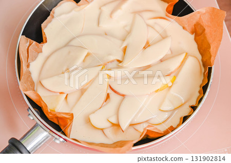 將麵糊倒入煎鍋中的蘋果上。 將麵糊倒入煎鍋中的蘋果上。 131902814