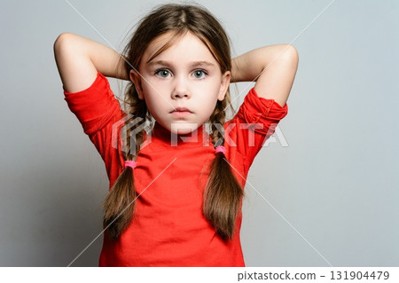 A little girl holds her hands behind her head, bending them at the elbows. A little girl holds her hands behind her head, bending them at the elbows. 131904479