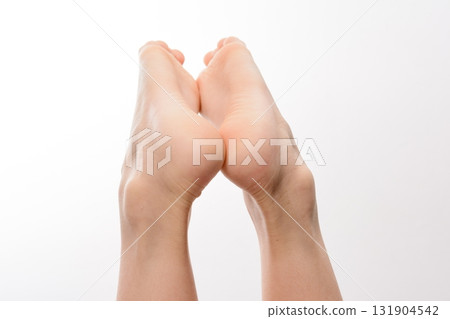 Close-up of two bare feet raised against a white background. Soft, smooth skin is visible. Ideal for beauty or health related projects. Close-up of two bare feet raised against a white background. Soft, smooth skin is visible. Ideal for beauty or health related projects. 131904542