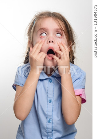 Young girl with surprised expression, eyes wide open, mouth agape, hands covering face. A candid shot of childlike wonder. 131904575