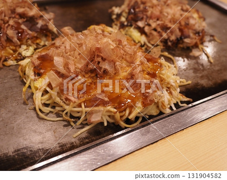 Three okonomiyaki on a hot plate 131904582
