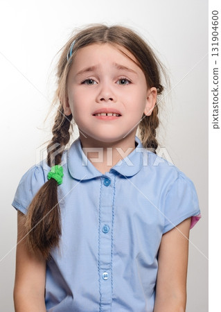Young girl with a thoughtful expression, wearing a light blue shirt. Her hair is in braids. Young girl with a thoughtful expression, wearing a light blue shirt. Her hair is in braids. 131904600