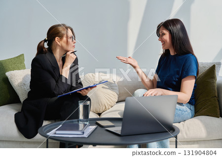 Female patient talking to psychotherapist psychologist, sitting together in office 131904804