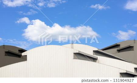 Modern industrial warehouse architecture with curved roof and blue sky 131904927