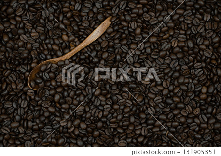 a hint of subtle taste and the ability to enjoy the taste of coffee alone or with friends, these coffee beans are on spoons and scattered on the surface as a background 131905351