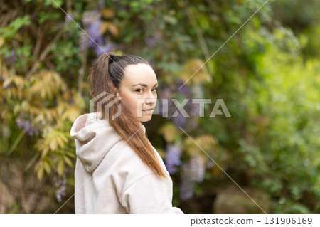Young woman looking back in green garden 131906169