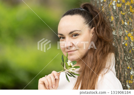 Young woman holding sprig of fresh flower buds 131906184
