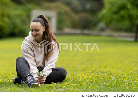 Young woman enjoying nature holding small flowers 131906189