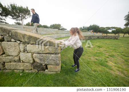 Young woman jumping over stone wall in park Young woman jumping over stone wall in park 131906190