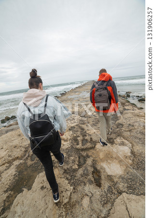 Couple walking on pier exploring dynamic ocean landscape Couple walking on pier exploring dynamic ocean landscape 131906257