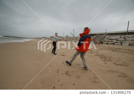 Young people playing on sandy beach during gloomy day Young people playing on sandy beach during gloomy day 131906270