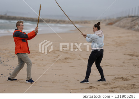 People playing with sticks on sandy beach People playing with sticks on sandy beach 131906295