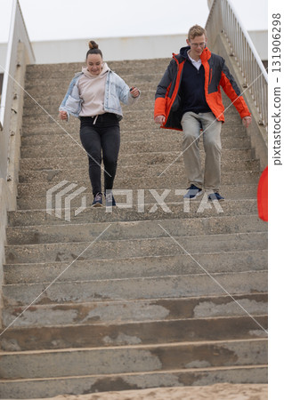 Young adults descending concrete stairs with energy Young adults descending concrete stairs with energy 131906298