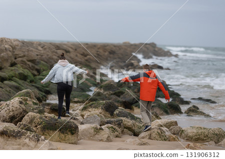 Young couple balancing on rocky beach exploring coastline 131906312