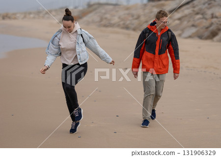 Young couple walking on sandy beach during leisure time Young couple walking on sandy beach during leisure time 131906329