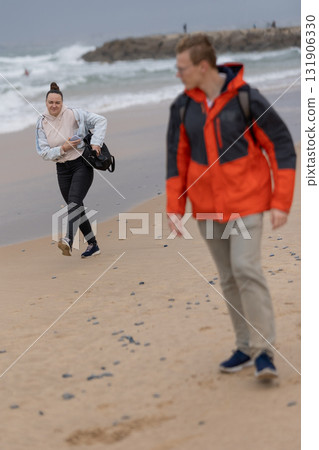 People walking on sandy beach on an overcast day 131906330