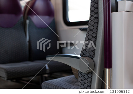 Train seat with foldable armrest, showcasing functional and compact design. Ergonomic armrest contrasts with patterned seat fabric, offering comfort and practicality for passengers 131906512