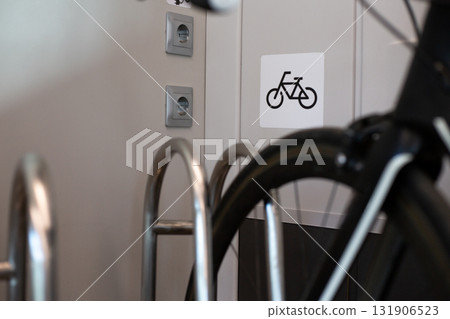 Close up image of bicycle placed in bike rack inside train, with bike symbol on wall indicating bike friendly facilities for passengers traveling with their bicycles Close up image of bicycle placed in bike rack inside train, with bike symbol on wall indicating bike friendly facilities for passengers traveling with their bicycles 131906523