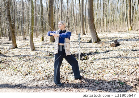 Young woman stretching in forest during nordic walking training 131906647
