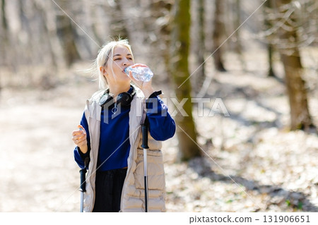 Young woman nordic walking in forest during winter sunny day 131906651