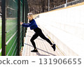 Young sportswoman stretching legs outdoor using a fence 131906655