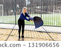 Young woman carrying yoga mat walking near sports field 131906656
