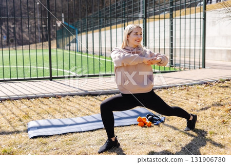 Young woman stretching legs practicing yoga asana outdoors in the park 131906780