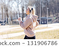 Young sporty woman running and listening to music with wireless headphones in the park 131906786