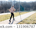 Young sportswoman running in the park listening music with headphones 131906787